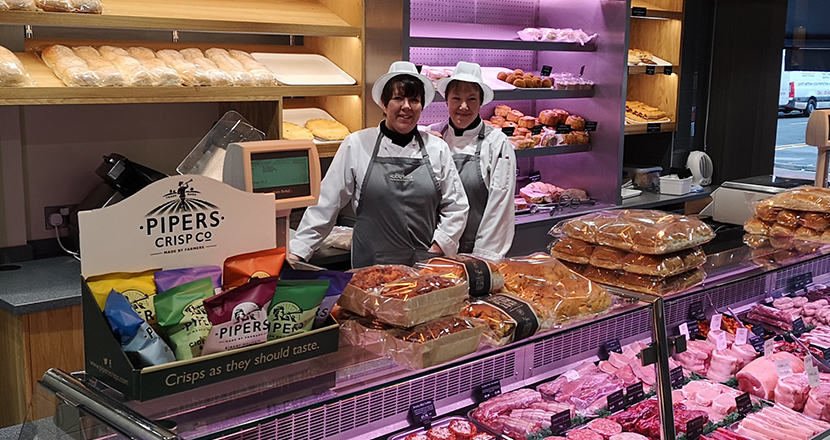 A photography of staff standing next to the meat counter in Birketts