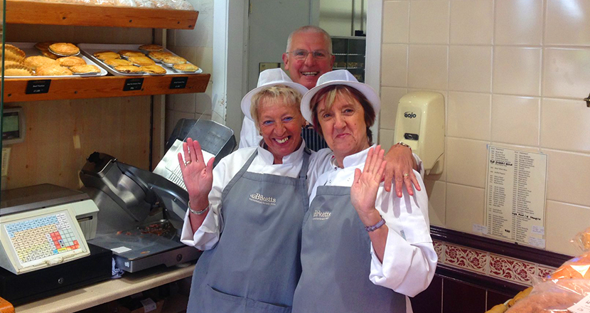 Two female staff members waving at the camera