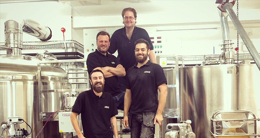 A photograph of 4 men next to a distillery