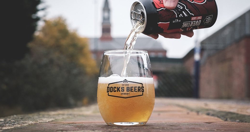 A photograph of a man pouring beer from a can into a glass