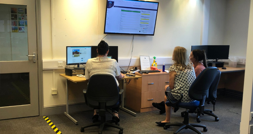 A group of three women working at a computer