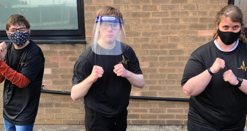 Three people with face shields exercising
